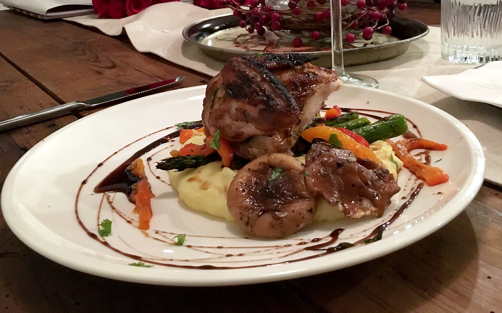 Plated dinner over potato pur&eacute;e with asparagus, roasted peppers and a dark reduction