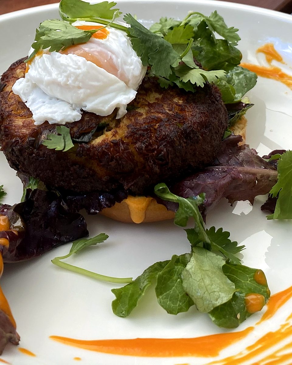 Golden pan-fried cake topped with a poached egg, cilantro and a bright pepper sauce